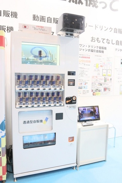 日本マシンサービスのブースに展示されていた「防犯自販機」。上部にあるボックスの中にネットワークカメラが内蔵されている。他にも防災用途を想定したサイネージ付きの自販機なども展示されていた（撮影：編集部）