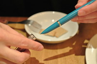 写真：ペン軸のカラリングについて語る岩井氏と同氏愛用の万年筆、ときにこのペン先から生み出される言葉が顧客の安全を支える